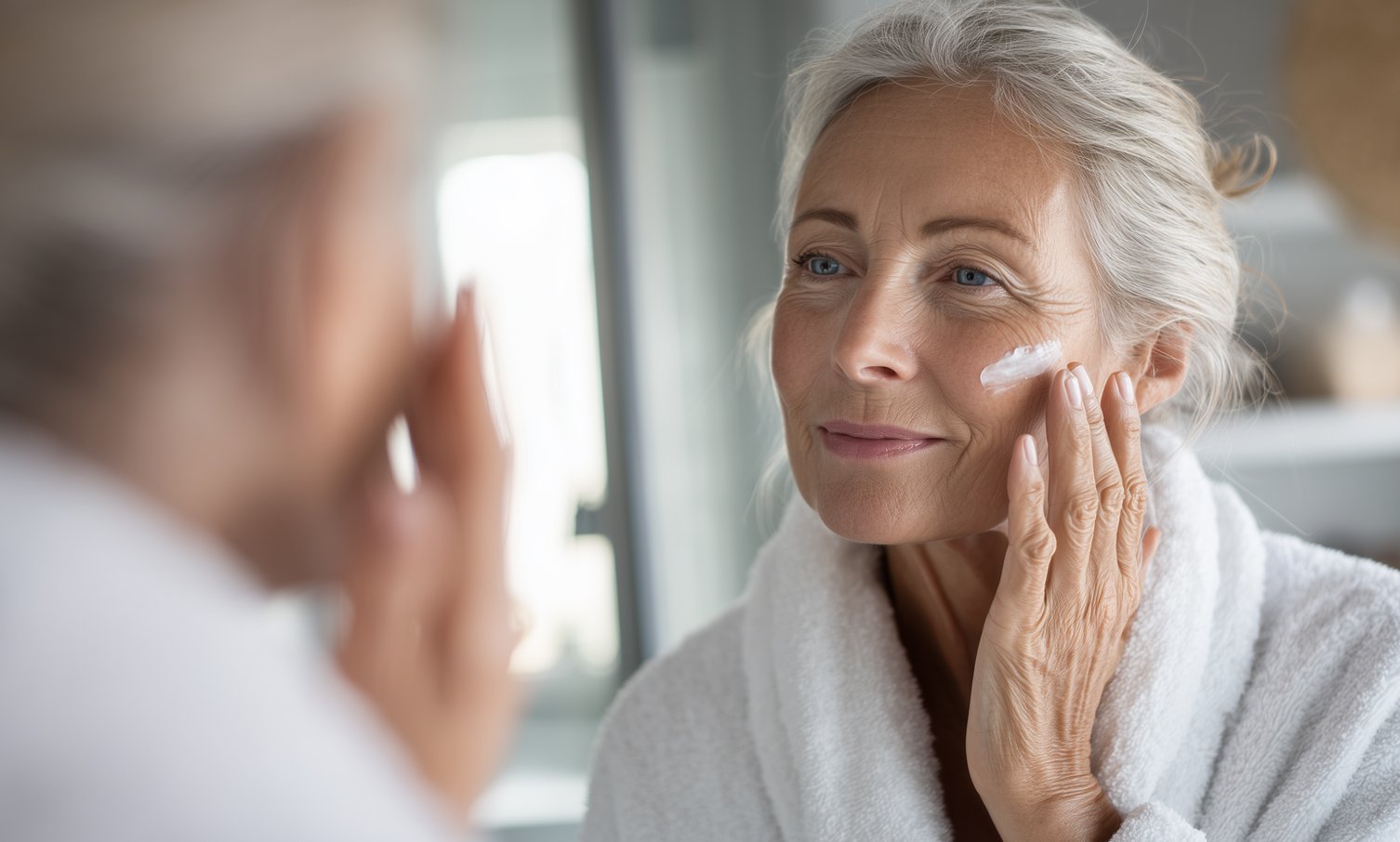 older woman applies cream on the face