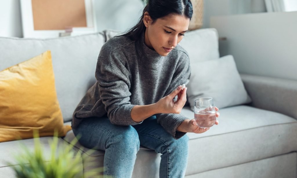 medical_woman-taking_medicine_35-calm_water-glass_sofa_full-body_landscape-web-aspect-ratio-1506-906