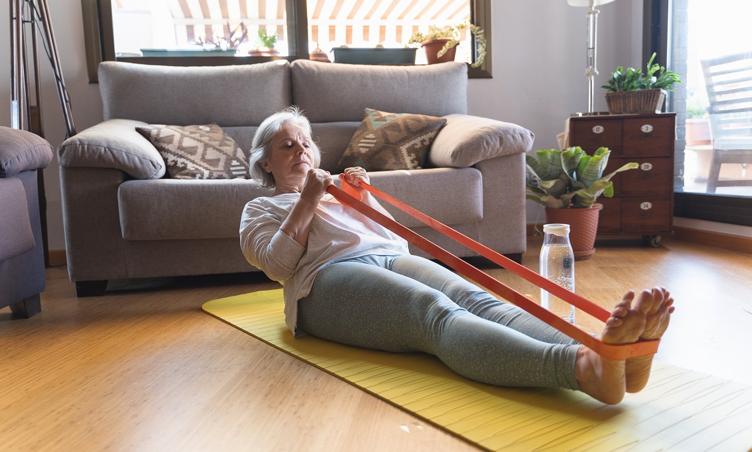 older woman making resistance training at home rubber bands