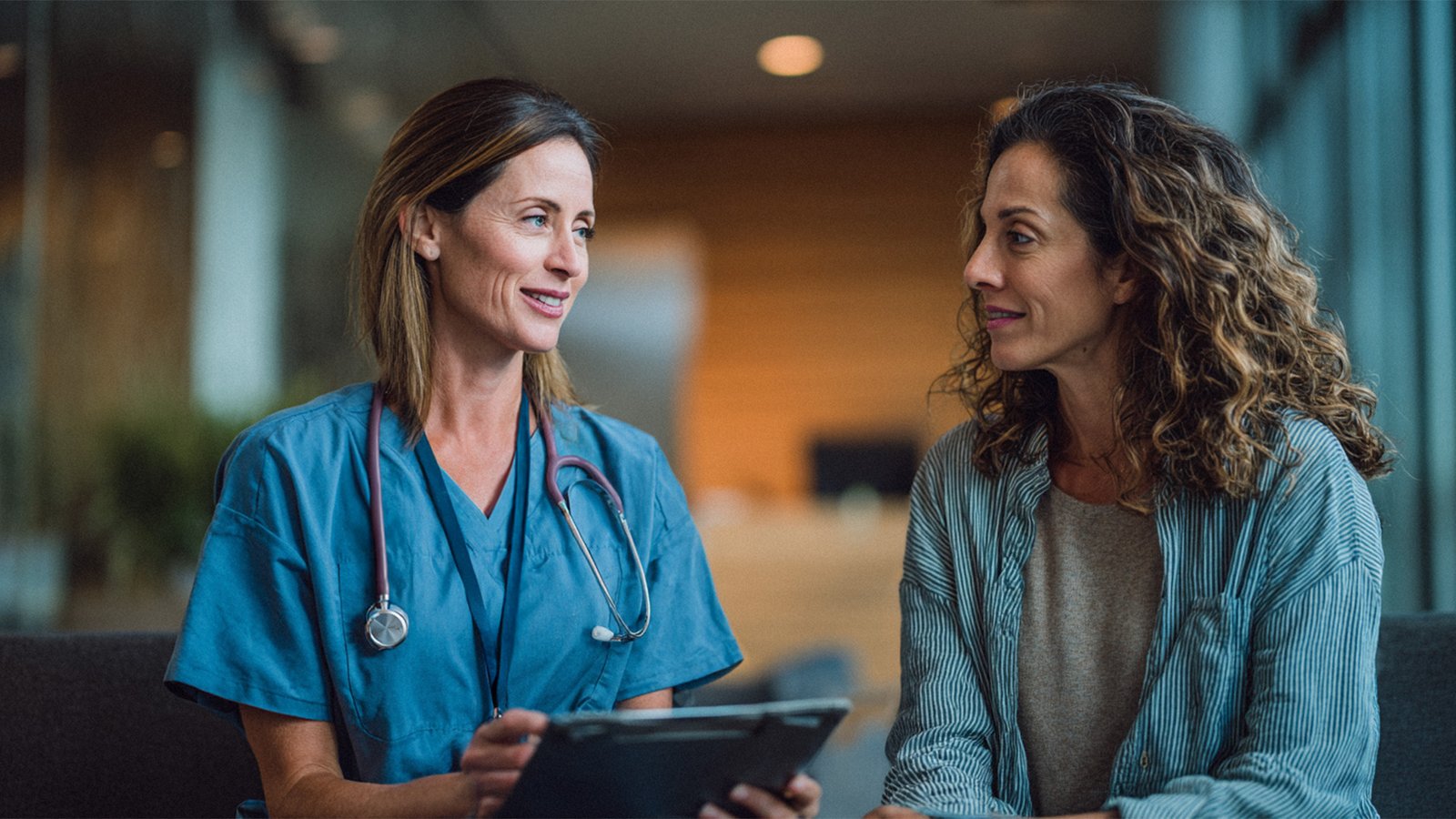 A nurse talking with a woman during a medical consultation in a modern clinic.